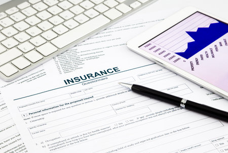 insurance questionnaire and tablet on office tableの写真素材