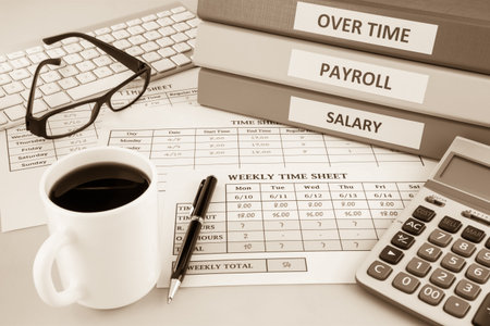Human resources documents: payroll, salary and employee  time sheets place on office table with cup of coffee and calculator, sepia toneの写真素材