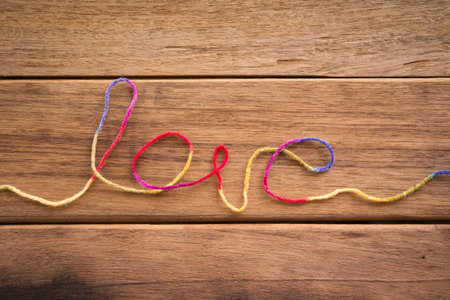 Sweet love word from colorful yarn place on wood texture, wedding and valentineの写真素材