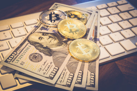 US dollar 100 banknotes and Cryptocurrency, lighting and focusing on gold Bitcoin on white modern...