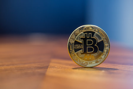 Cryptocurrency symbol sign, focus on gold metal Bitcoin stack on wooden table, blur dark blue wall...