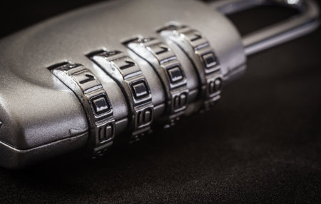 Close up 4 digits code number on silver combination padlock on black background, dim light dark tone. data protection, key management, password access, security encryption concepts.の写真素材