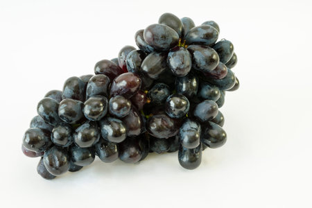 Bunch of black seedless grapes (Vitis vinifera) with water drops on a white background