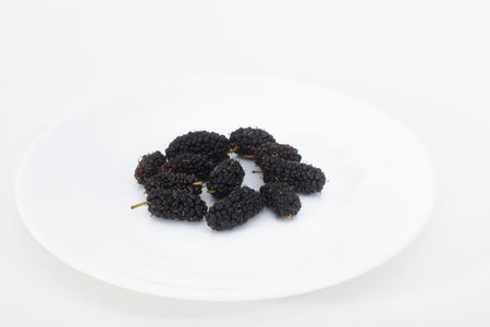 White plate with ripe mulberries on a white backgroundの写真素材