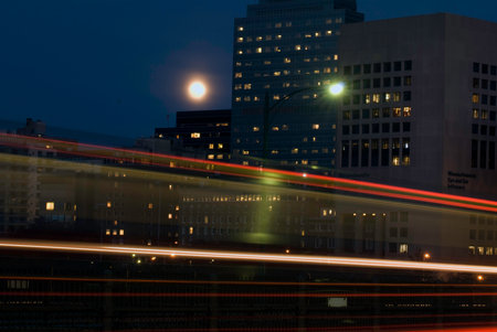 Fast moving commuter train leaves a red streak beneath the rising moon