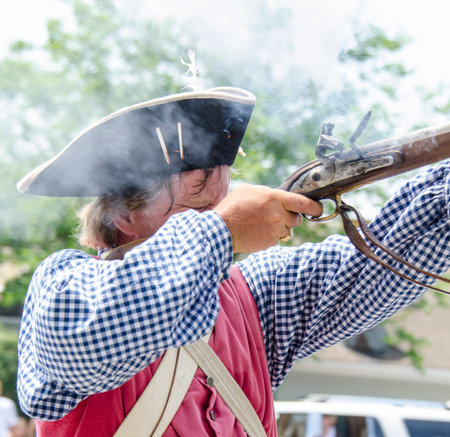 BRISTOL, RHODE ISLAND - JULY 4, 2011:  Revolutionary War reenactor fires his musket in Fourth of July parade in Bristol, Rhode Island, an annual tradition since 1785のeditorial素材