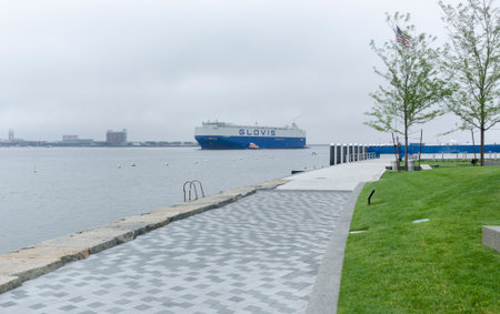 BOSTON, MASSACHUSETTS, USA - July 7, 2016: Tugboats nudge cargo ship past Fan Pier in South Boston on foggy morningのeditorial素材