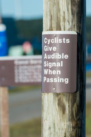 Sign warns cyclists to signal when passing  on bike path along Cape Cod Canalの写真素材