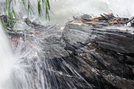 Icy water cascading through rocky cut on hillsideの写真素材