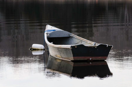 Old skiff bobbing at mooring on calm afternoon