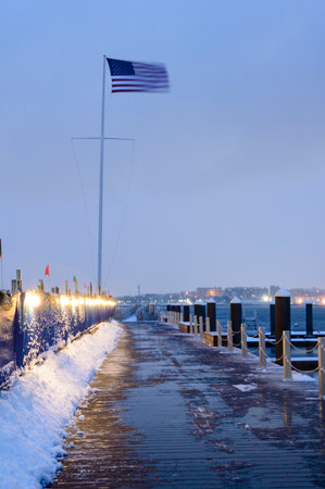 Fierce wind straightens American flag on winter morning near construction project along Fan Pier in South Bostonの写真素材
