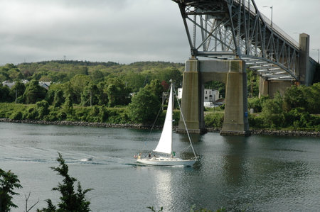 Cape Cod Canal, Massachusetts, USA - June 19, 2005: Sailboat passing under Sagamore Bridge on Cape Cod Canalのeditorial素材