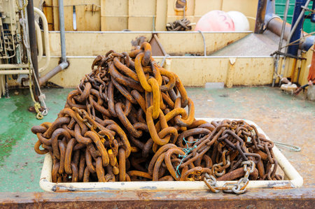 Rusty chain of mixed sizes stored in a tub on fishing boatの写真素材