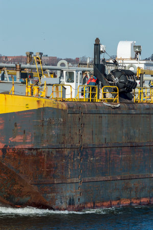 New Bedford, Massachusetts, USA - February 3, 2018: Crewman scanning river as barge approaches...