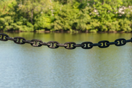 Chain strung between bollards to help keep pedestrians out of the Charles River in Walthamの写真素材