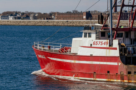 New Bedford, Massachusetts, USA - April 11, 2019: Commercial fishing vessel Endurance leaving New Bedford with factory and residential area in backgroundのeditorial素材