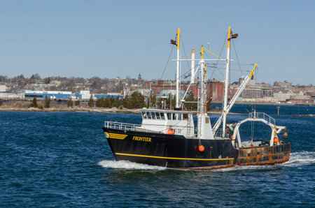 New Bedford, Massachusetts, USA - April 4, 2019: Scalloper Frontier heading to sea on Acushnet River with waterfront in backgroundのeditorial素材