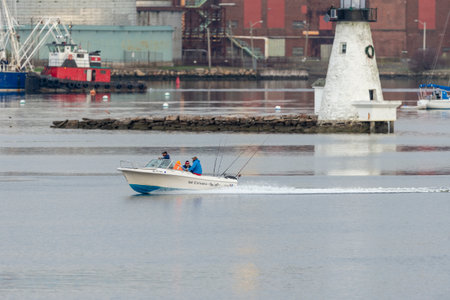 New Bedford, Massachusetts, USA - May 1, 2019: Powerboat No Excuses with four fishermen passing Palmer Island Light Station in New Bedford harborのeditorial素材