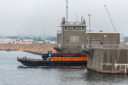 New Bedford, Massachusetts, USA - July 30, 2019: Equipment barge Henri being pushed through hurricane barrier by tug Roy Boys on foggy summer morningのeditorial素材