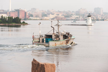 Fairhaven, Massachusetts, USA - July 30, 2019: Lobsterboat Silver Key, hailing port N. Weymouth, Massachusetts, crossing New Bedford harbor on hazy, windless morningのeditorial素材