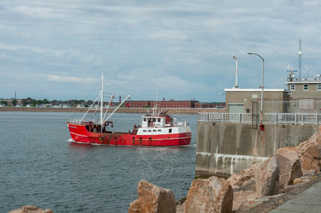 Fairhaven, Massachusetts, USA - June 7, 2019: Commercial fishing vessel Ambassador leaving Fairhaven with New Bedford factories and residential neighborhood in backgroundのeditorial素材