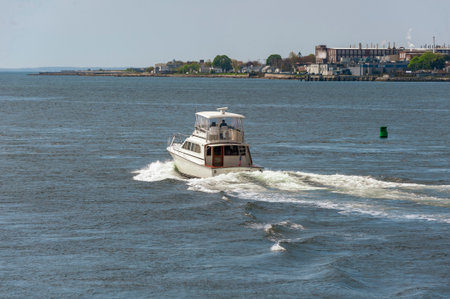New Bedford, Massachusetts, USA - May 16, 2019: Powerboat Will Power heading toward Buzzards Bay on Acushnet River with factory in backgroundのeditorial素材