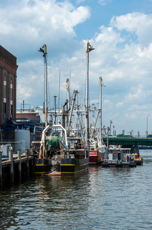 New Bedford, Massachusetts, USA - July 4, 2019:  Commercial fishing vessel Susan Rose, hailing port Point Judith, Rhode Island, moored at ice house with other boats on summer afternoonのeditorial素材