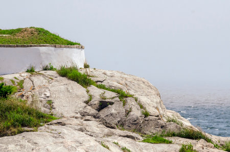 Rocky bluff at Fort Phoenix overlooking choppy Acushnet River on foggy morningの写真素材
