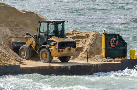 New Bedford, Massachusetts, USA â€“ October 7, 2019: Bucket loader and sand on barge being...