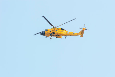 New Bedford, Massachusetts, USA - August 10, 2018: U. S. Coast Guard MH-60 Jayhawk helicopter flying over New Bedford harbor while USCG training cutter Eagle is dockingのeditorial素材