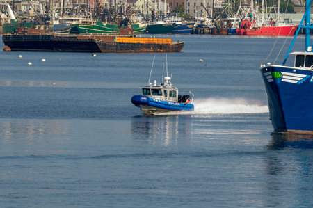 New Bedford, Massachusetts, USA - August 17, 2018: New Bedford Police Department patrol boat speeding past fishing boat and barge on its way toward Buzzards Bayのeditorial素材
