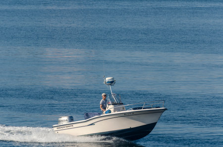 New Bedford, Massachusetts, USA - August 5, 2018: Powerboat skipper easing back on throttle as he...