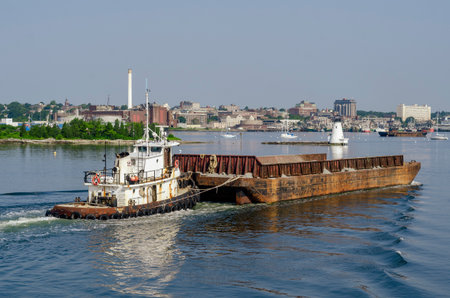 New Bedford, Massachusetts, USA - July 2, 2018: Tug Sirius pushing empty barge past Palmer Island Light Station in New Bedford harborのeditorial素材