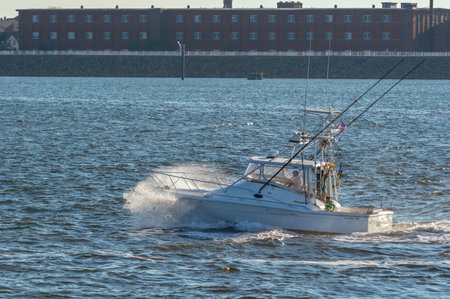 New Bedford, Massachusetts, USA - September 5, 2018: Sport fishing boat Wild Horses crashing through evening chop in New Bedford outer harbor with mill in backgroundのeditorial素材