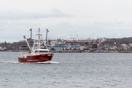 New Bedford, Massachusetts, USA - March 12, 2018: Fishing vessel Concordia passing shoreline factories in New Bedford, Massachusetts in early evening, entering port in advance of approaching nor'easterのeditorial素材