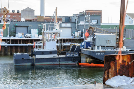New Bedford, Massachusetts, USA - March 15, 2018: Tug Vilkikas butted up against barge Cher 107  alongside pier under construction in New Bedford harborのeditorial素材