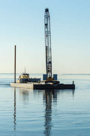 New Bedford, Massachusetts, USA - February 27, 2018: Tug Michael, hailing port Groton, Connecticut, pushing Mohawk 672-13 barge carrying heavy construction crane in New Bedford outer harborのeditorial素材
