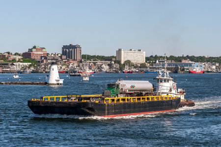New Bedford, Massachusetts, USA - June 8, 2020: Tug Sirius passing lighthouse as she pushes equipment barge with tanker truck aboardのeditorial素材