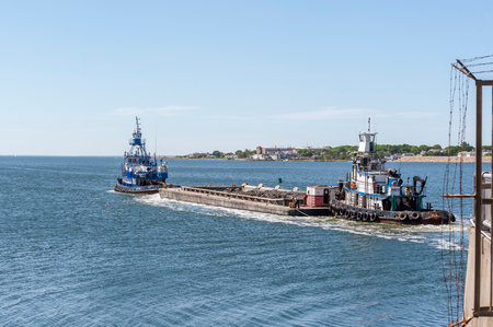 New Bedford, Massachusetts, USA - June 8, 2020: Crewman releasing lines to tug Meridian after tugs move barge through hurricane barrier on a morning of tricky winds and currentsのeditorial素材