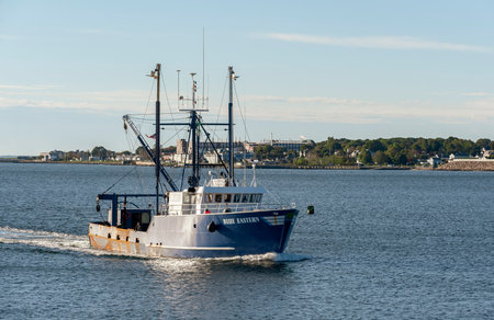 New Bedford, Massachusetts, USA - October 16, 2018: Scalloper Blue Eastern crossing New Bedford outer harbor with factory in backgroundのeditorial素材