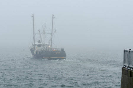 New Bedford, Massachusetts, USA - April 4, 2018: Commercial fishing boat Westport leaving hurricane barrier for foggy Buzzards Bayのeditorial素材