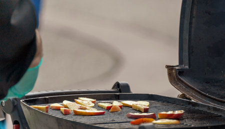 Chef cooking slices of apple on a grilleの写真素材