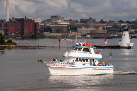 Fairhaven, Massachusetts, USA - July 1, 2020: Sun spotlights charter fishing boat Bounty Hunter through break in storm cloudsのeditorial素材