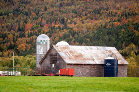 New Hampshire, USA - September 30, 2009: Barn and silos against mountainside with trees in fall colorsのeditorial素材