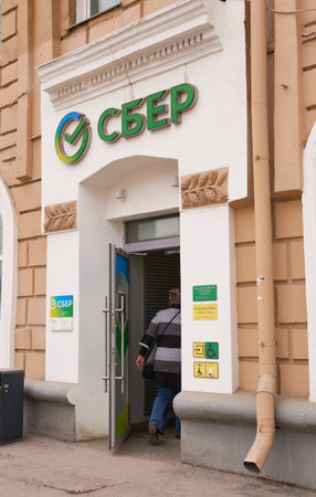 Novosibirsk, Siberia, Russia - April, 19, 2022. An older woman enters the Sberbank branch. The largest universal bank in Russia and Eastern Europe.のeditorial素材