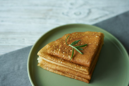 Pancakes with a sprig of rosemary on a green plate. breakfast concept.の写真素材