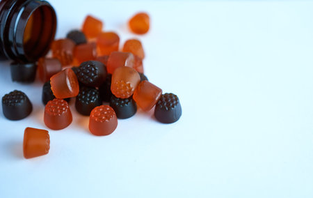 A child chews vitamins on a white background close-up with a brown bottleの写真素材