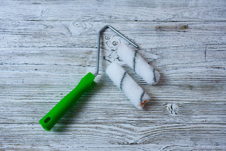 roller for painting the ceiling and walls on a wooden background top view