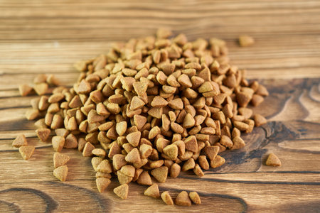 Dry cat food scattered on a wooden background.
