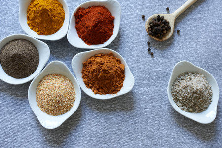 An assortment of spices in bowls for different dishes. Salt and spices, different types of peppers,...